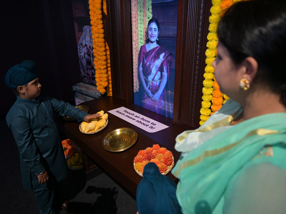 Mother and child examining a display about Hindu puja.